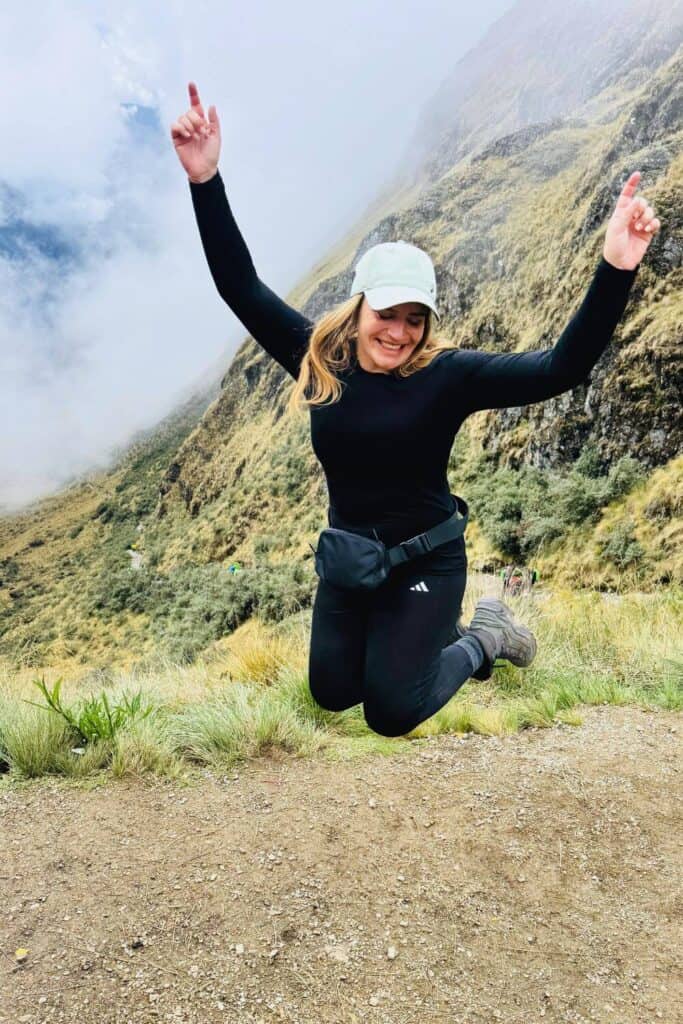 Fröhliche Frau beim Springen im Gebirge, Spaß beim Bergwandern, Natur erleben, Outdoor-Aktivitäten, alpine Landschaft.