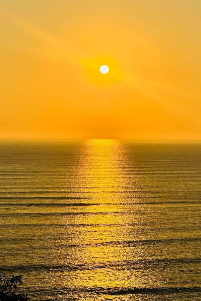 Sonnenuntergang über dem Meer mit goldener Reflexion und warmem Himmel.