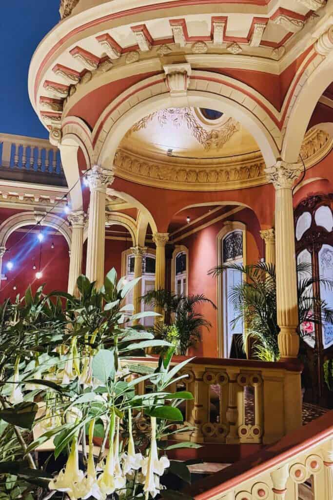 Eleganter Innenraum mit barockem Stil, Säulen und grünen Pflanzen.